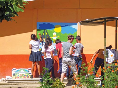 Estudiantes de la Escuela Pijije junto a Freda Brenes, la artista pintando el mural de la Escuela Pijije.